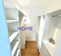 Šatník v 3-pokojovém bytě s úložnými prostory a podlahou s dřevěným dekorem.