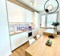 Kuchyně ve 3-pokojovém bytě s bílými skříňkami a podlahou s dřevěným dekorem.