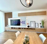 Světlý obývací pokoj ve 3-pokojovém bytě s podlahou s dřevěným dekorem a moderním liniovým osvětlením.