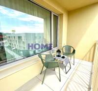 Balkon s výhledem, posezením a dekoračním stolkem v 3pokojovém bytě.