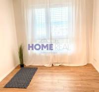 Pokoj s podlahou s dřevěným dekorem a bílými záclonami ve 3-pokojovém bytě.