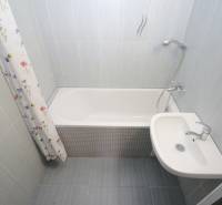 Koupelna s vanou a umyvadlem v 3-pokojovém bytě s dlažbou.