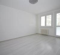 Pokoj v 3-pokojovém bytě s podlahou s dřevěným dekorem a velkými okny.