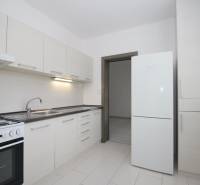 Kuchyně v 3-pokojovém bytě s bílými skříňkami a bílou podlahou.