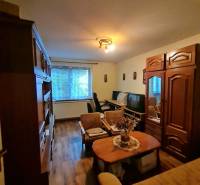 Obývací pokoj v rodinném domě s nábytkem a podlahou s dřevěným dekorem.