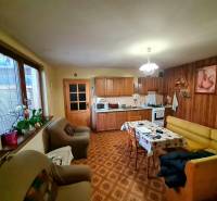 Kuchyně v rodinném domě s dřevěným dekorem, sedací soupravou a jídelním stolem.