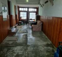 Chodba v rodinném domě s jednoduchým nábytkem, stěnou s dřevěným obložením a loveckými trofejemi.