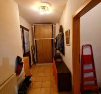 Chodba v rodinném domě s dlažbou, botníkem, věšákem a skříní.