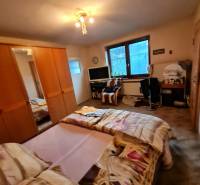 Ložnice s postelí, skříní a stolem v rodinném domě.