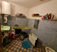 Koupelna v rodinném domě s vanou, umyvadlem, regály a topným tělesem.