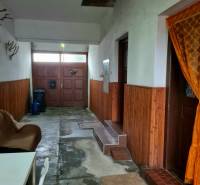 Interiér rodinného domu se vstupními dveřmi, židlí a dekorací na stěnách.