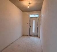 Chodba v rodinném domě s jednoduchým osvětlením a plastovými dveřmi.