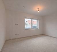 Prostorný pokoj v rodinném domě s oknem s výhledem na jiný dům.