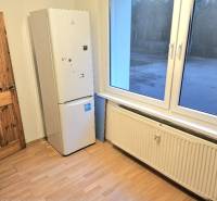 Kuchyňský kout v 3-pokojovém bytě se spotřebičem a podlahou s dřevěným dekorem.