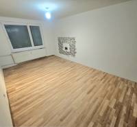 Obývací pokoj s podlahou s dřevěným dekorem a oknem ve 3-pokojovém bytě.