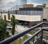 Výhled z balkonu na obchodní centrum Nivy v Bratislavě s moderní architekturou.