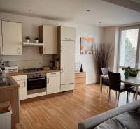 Kuchyně v 2-pokojovém bytě s jídelním stolem a podlahou s dřevěným dekorem.