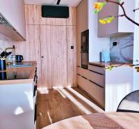 Kuchyně v 3-pokojovém bytě s dřevěným dekorem a vestavěnými spotřebiči.