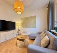 Obývací pokoj v 2-pokojovém bytě s podlahou s dřevěným dekorem, sedačkou a TV.