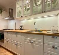 Světlá kuchyně v 2-pokojovém bytě s podlahou s dřevěným dekorem a bílými skříňkami.