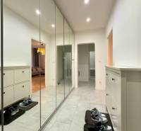 Předsíň s velkou vestavěnou skříní a botníkem v 2-pokojovém bytě na podlaze s dlažbou.