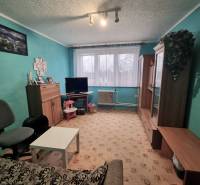 Obývací pokoj v 3-pokojovém bytě s tyrkysovými stěnami, nábytkem a kobercovou podlahou.