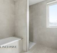 Koupelna v rodinném domě s vanou, sprchovým koutem a oknem bez záclon.