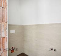 Interiér rodinného domu s neomítnutou cihlovou stěnou a obkladem v koupelně.