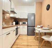 Kuchyně v 2-pokojovém bytě s bílými skříňkami a podlahou s dřevěným dekorem.