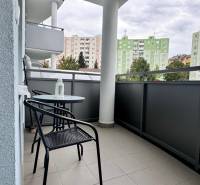 Balkon 2-pokojového bytu na Halalovce v Trenčíně se stolem a židlemi, výhled na paneláky.