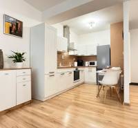 Kuchyně v 2pokojovém bytě s bílými skříňkami a podlahou s dřevěným dekorem.