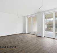 Prostorný pokoj v rodinném domě s velkými okny a podlahou s dřevěným dekorem.