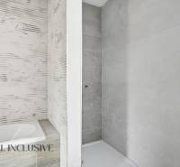 Koupelna v rodinném domě s vanou a sprchovým koutem, světlé obklady.