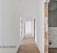 Chodba v rodinném domě s bílými stěnami a podlahou s dřevěným dekorem.