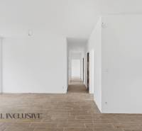 Bílá chodba v rodinném domě s podlahou s dřevěným dekorem a prosklenými dveřmi do dvora.