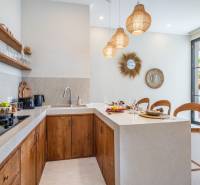 Interiér vily s kuchyňským koutem, dřevěnými skříňkami a dekorativními zrcadly.