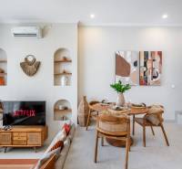 Obývací pokoj vily s televizí, jídelním stolem a dekorativními prvky na stěnách.