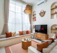 Světlý obývací prostor ve vile s pohovkou, TV a dekorativním osvětlením.