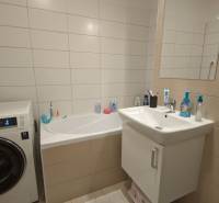 Koupelna s vanou, pračkou a umyvadlem v 2-pokojovém bytě.