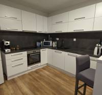 Kuchyně v 2-pokojovém bytě s podlahou s dřevěným dekorem a bílými skříňkami.