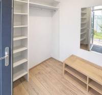 Chodba s policemi a podlahou s dřevěným dekorem v 3-pokojovém bytě.