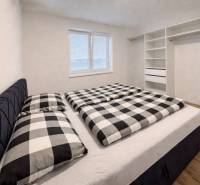 Ložnice v 3-pokojovém bytě s vestavěnou skříní a podlahou s dřevěným dekorem.