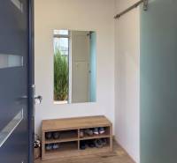 3pokojový byt s lavicí na boty, zrcadlem a podlahou s dřevěným dekorem.