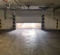 Otevřená garážová vrata vedou ven, okolí je osvětlené nepřímým světlem.