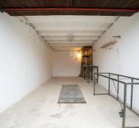 Prostorný interiér garáže s kovovými policemi a bílými stěnami.