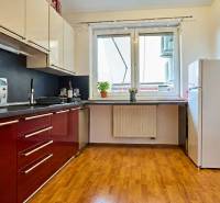 Kuchyně v 2-pokojovém bytě s červenými skříňkami a podlahou s dřevěným dekorem.