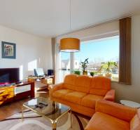 Obývací pokoj v 2-pokojovém bytě s oranžovou sedačkou a TV, podlaha s dřevěným dekorem.