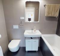 Koupelna s vanou, umyvadlem, závěsnou toaletou a pračkou v 2-pokojovém bytě.