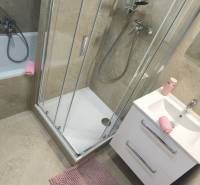 Koupelna ve 4-pokojovém bytě s vanou, sprchovým koutem a světlými dlaždicemi.