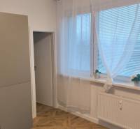 Interiér 4-pokojového bytu s podlahou s dřevěným dekorem, kuchyně s moderními spotřebiči.